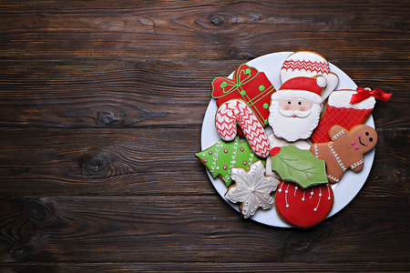 Plate full of tasty Christmas cookies on a brown wooden tableの写真素材