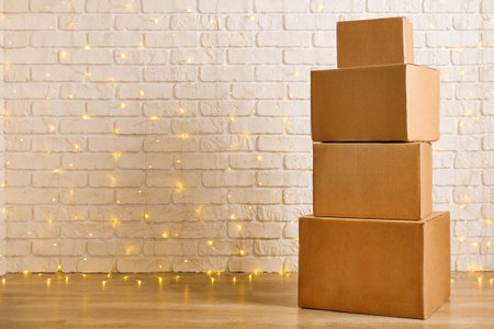 Stack of four blank brown freight boxes, different size, brick wall with Christmas lights on...