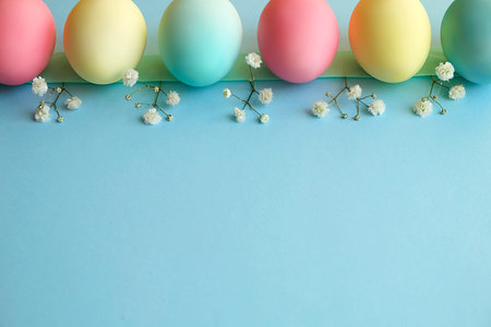 Beautiful easter table setting composition. A row of pastel color eggs, pink, blue and yellow, white...