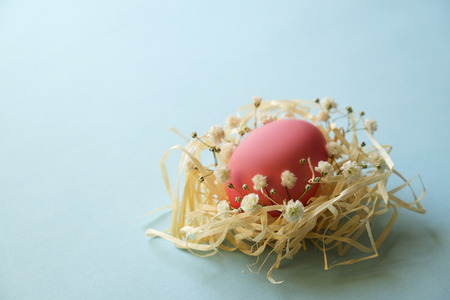 Beautiful easter table setting composition. Pastel color eggs in hay nest, pink, blue and yellow on table top. Blank Happy Easter greeting card. Top view, festive background, flat lay, copy space.の写真素材