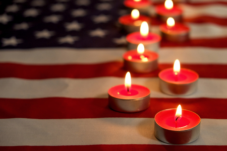 Mourning candles burning on USA American national flag background. Memorial weekend, patriot veterans day, 9/11 National Day of Service & Remembrance. Moment of silence concept. Close up, copy space.の写真素材