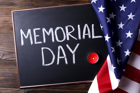 Memorial day weekend text written on wooden black chalkboard, candle w/ USA flag background. United States of America stars & stripes patriot veteran remembrance symbol. Close up, copy space, top viewの写真素材
