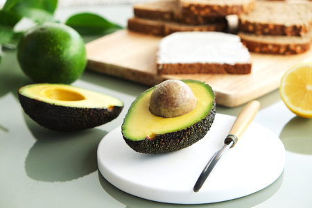 Vegan rye bread toast sandwich with lactose free cheese spread. Nutrient dense avocado fruit full of heart healthy monounsaturated fat on wooden board. Close up, copy space, top view, background.の写真素材