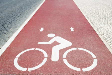 Paved red bike lane texture with the road sign, movement direction and bicycle stencil. Close up,...