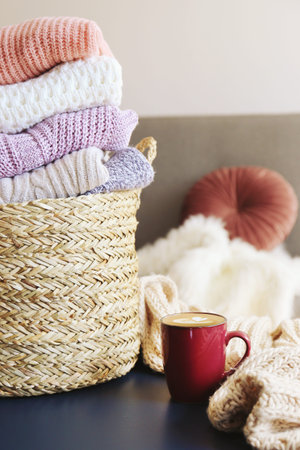 Bunch of stacked knitted pastel color sweaters with different knitting patterns perfectly folded in...