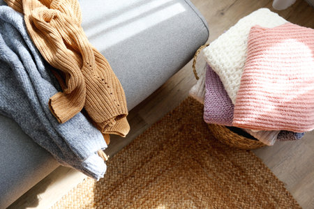 Stack of cozy knitted sweaters in wicker basket
