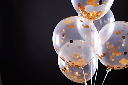 Translucent helium balloon with golden confetti inside over paper textured wall background with a lot of copy space for text. Black friday sale concept. Close up crop image.の写真素材