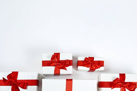 Bunch of christmas presents wrapped in red and white paper tied with shiny silk bow. Multiple new years gifts in different wrapping. Top view, close up, copy space, background, flat layの写真素材