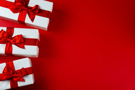 Bunch of christmas presents wrapped in red and white paper tied with shiny silk bow. Multiple new...