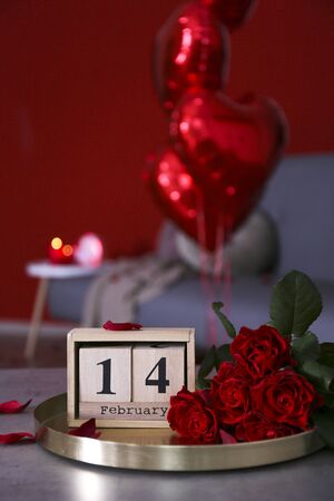 Wooden cube calendar with 14th february date, beautiful red roses bouquet. Happy st. valentine's day concept. Close up, copy space, front viewの写真素材