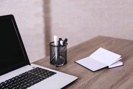 Creative workspace of a blogger. White laptop computer on wooden table in loft style office with...