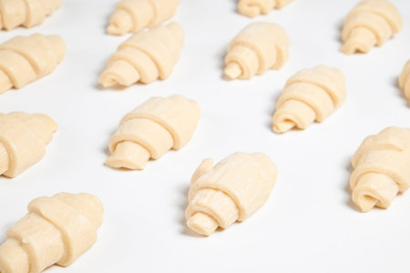 Close up studio shot of semi-finished frozen ready to cook croissant isolated on white background....