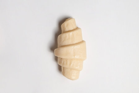 Close up studio shot of semi-finished frozen ready to cook croissant isolated on white background....