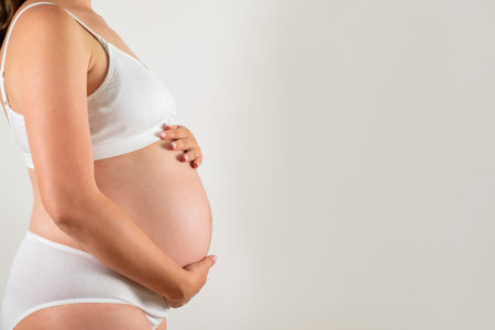 Close up of pregnant woman wearing supportive seamless maternity bra and maxi bottoms, arms on her...