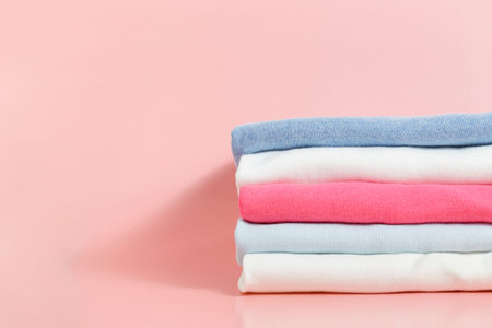 Stack of colorful perfectly folded clothing items. Pile of different pastel color shirts and...