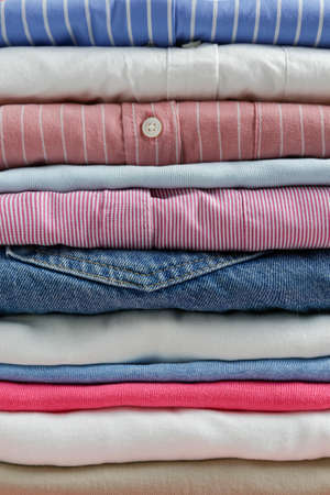 Cropped image with stack of colorful perfectly folded clothing items. Macro shot of pile of different pastel color shirts, sweaters & pants. Close up, copy space, background.の写真素材