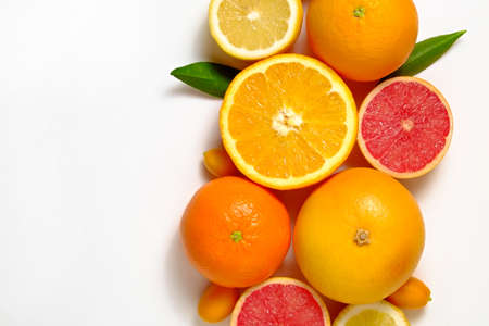 Close up image of juicy organic whole and halved assorted citrus fruits, green leaves & visible core texture, isolated white background, copy space. Vitamin C loaded food concept. Top view, flat lay.の写真素材