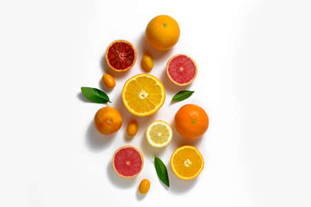 Close up image of juicy organic whole and halved assorted citrus fruits, green leaves & visible core texture, isolated white background, copy space. Vitamin C loaded food concept. Top view, flat lay.の写真素材