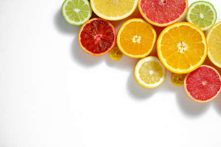 Close up image of juicy organic whole and halved assorted citrus fruits with visible core texture, isolated white background, copy space. Vitamin C loaded food concept. Top view, flat lay.の写真素材