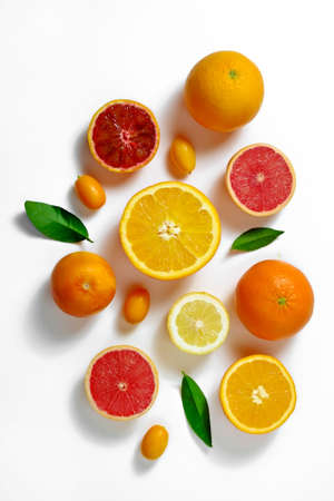 Close up image of juicy organic whole and halved assorted citrus fruits, green leaves & visible core texture, isolated white background, copy space. Vitamin C loaded food concept. Top view, flat lay.の写真素材