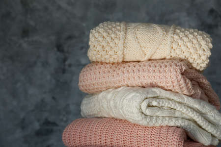 Bunch of knitted warm pastel color sweaters with different knitting patterns folded in stack, clearly visible texture. Stylish fall / winter season knitwear clothing. Close up, copy space for text.の写真素材