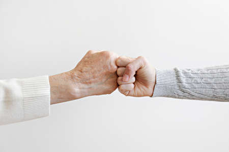 Two women of different age fist bumping over white wall background. Grandmother bonding with her granddaughter. Close up, copy space for text, isolated.の写真素材