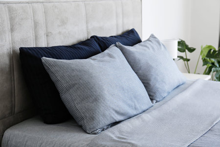 Hotel room with freshly made king sized bed with headboard, perfectly clean and ironed sheets, puffy pillows in natural sun light. Kingsize bed in a furniture showroom. Close up, copy space for text.の写真素材