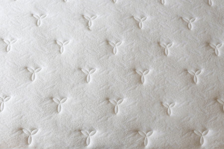 White orthopedic mattress top side surface pattern on unmade bed in the bedroom. Hypoallergenic foam mattress for proper spinal alignment and pressure point relief. Background, copy space, close up.の写真素材