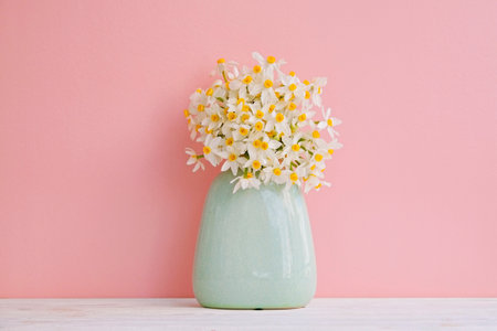 Lush bouquet of white-yellow daffodils in vintage turquoise vase isolated on pink background. Tender minimalistic spring flowers composition. Top view, copy space for text, flat lay, close up.の写真素材