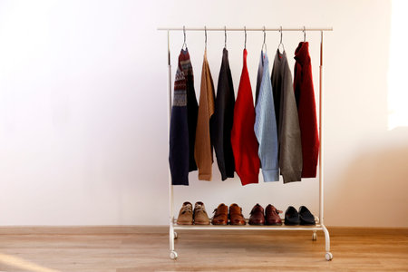 Clothes rack with different clothes on wooden floor, on light backgroundの写真素材