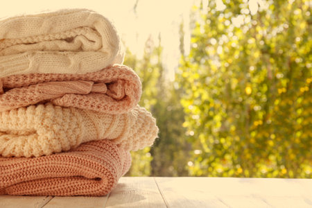 Stack of knitted sweaters on wooden table outdoors, closeupの写真素材
