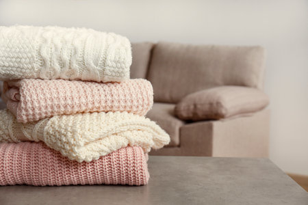 Stack of knitted sweaters on table in room, closeupの写真素材