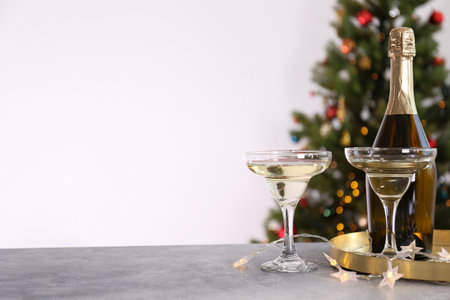 Glasses of champagne and bottle on table against blurred Christmas tree. Space for textの写真素材