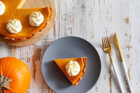 Pumpkin pie with whipped cream on a white wooden background.の写真素材