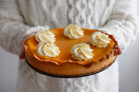 Woman holding a freshly baked pumpkin pie with whipped cream on top.の写真素材