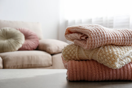 Stack of clean freshly laundered, neatly folded women's clothes on the table. Pile of shirts, dresses and sweaters on the table, concrete wall background. Copy space, close up, top view.の写真素材