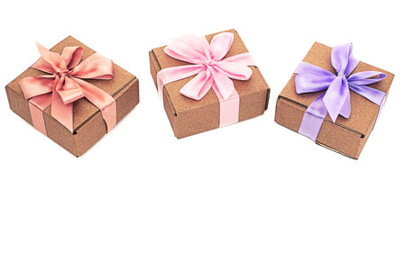 Three festive boxes with gifts tied with satin ribbon on a white background. Top view Flat layの写真素材