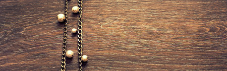 Banner Wooden dark vintage background. Metal gold chain with pearls. Top view Flat Lay