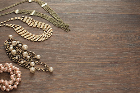 Decorative composition of women's jewelry on wooden dark background. Flat lay. The view from the top. The concept of fashion and beautyの写真素材