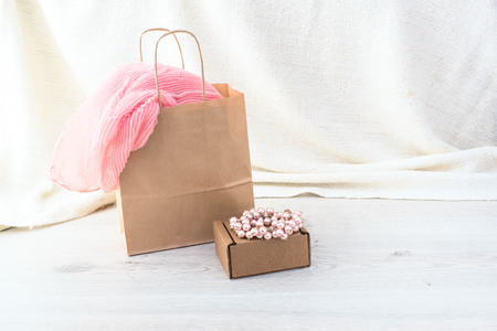 Set of shopping for women in Kraft packaging. Pink scarf in your bag for shopping, pearl bracelet on top of the box. Fashion accessoriesの写真素材