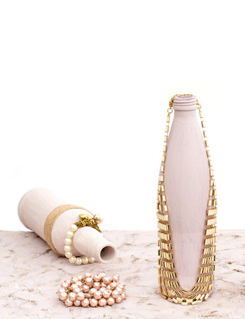 Bottle for home decoration on textured background. Paint, decor twine. Women's jewellery, necklace, bracelet.の写真素材