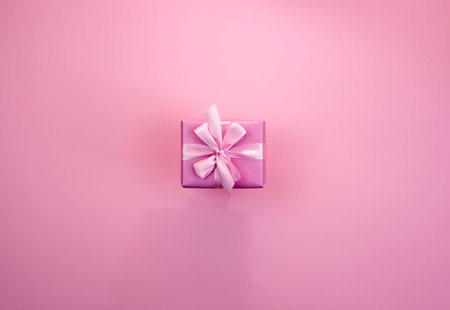 Decorative festive gift box with pink color on pink background. Flat flat top view