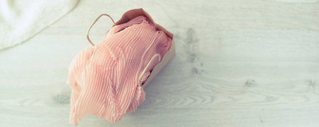 Banner A paper bag with purchases on the wooden light background. Light pink scarf in a paper bag...