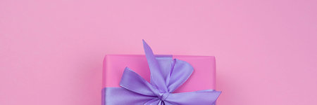 Banner Decorative festive gift box with pink color on pink background. Lilac satin ribbon bow.