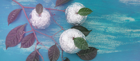 Banner Three apples wrapped in foil are natural green leaves. Wooden candy blue background. Flat lay top viewの写真素材