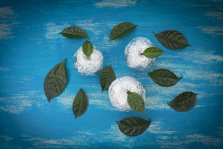 Three apples wrapped in foil are natural green leaves. Wooden candy blue background. Flat lay top viewの写真素材