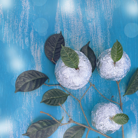 Three apples wrapped in foil are natural green leaves. Wooden candy blue background. Flat lay top viewの写真素材