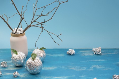 Apple tree wrapped in foil is a natural green leaves. Wooden candy blue background. Flat flat top viewの写真素材