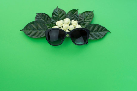 Background for text, the imitation of facial concept. Sunglasses natural leaves and white flowers on...