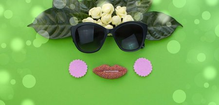 Banner Background for text, the imitation of facial concept. Sunglasses natural leaves and white flowers on a green background. Flat lay top viewの写真素材